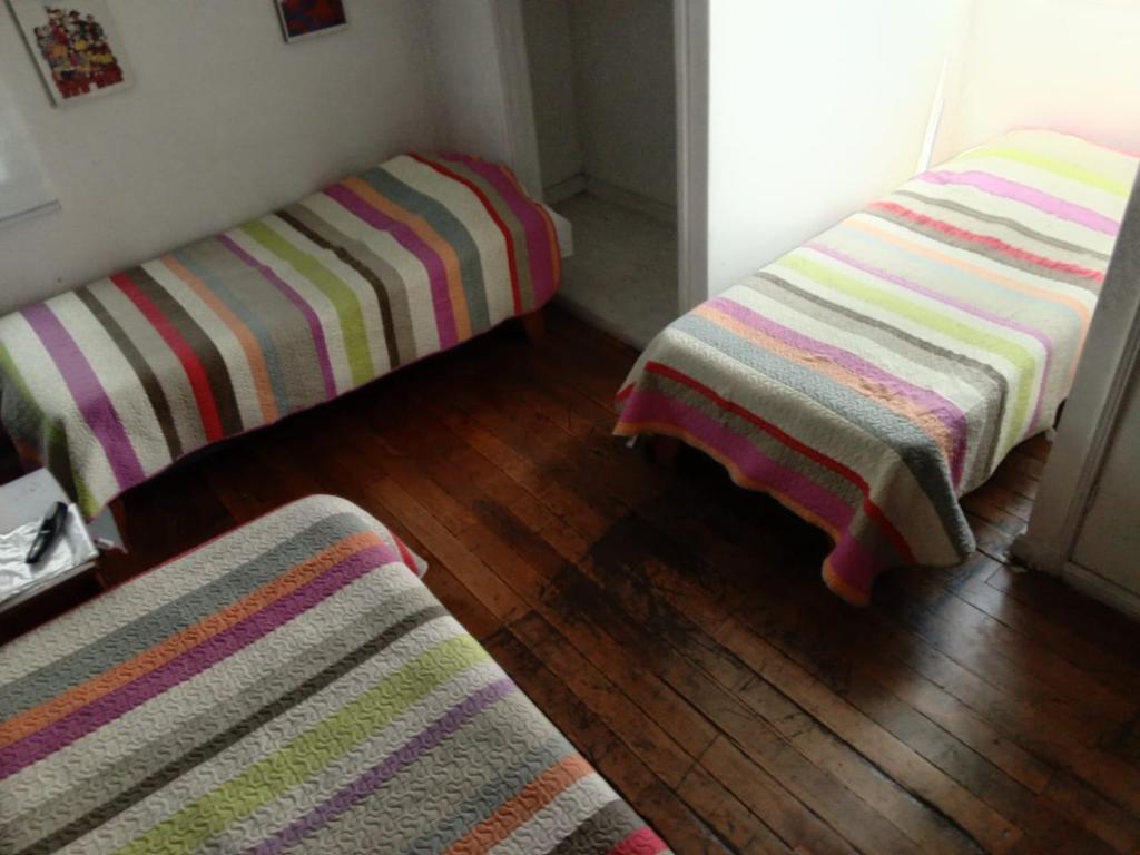 two striped beds in a room with a wooden floor at Hostal Salvador in Santiago