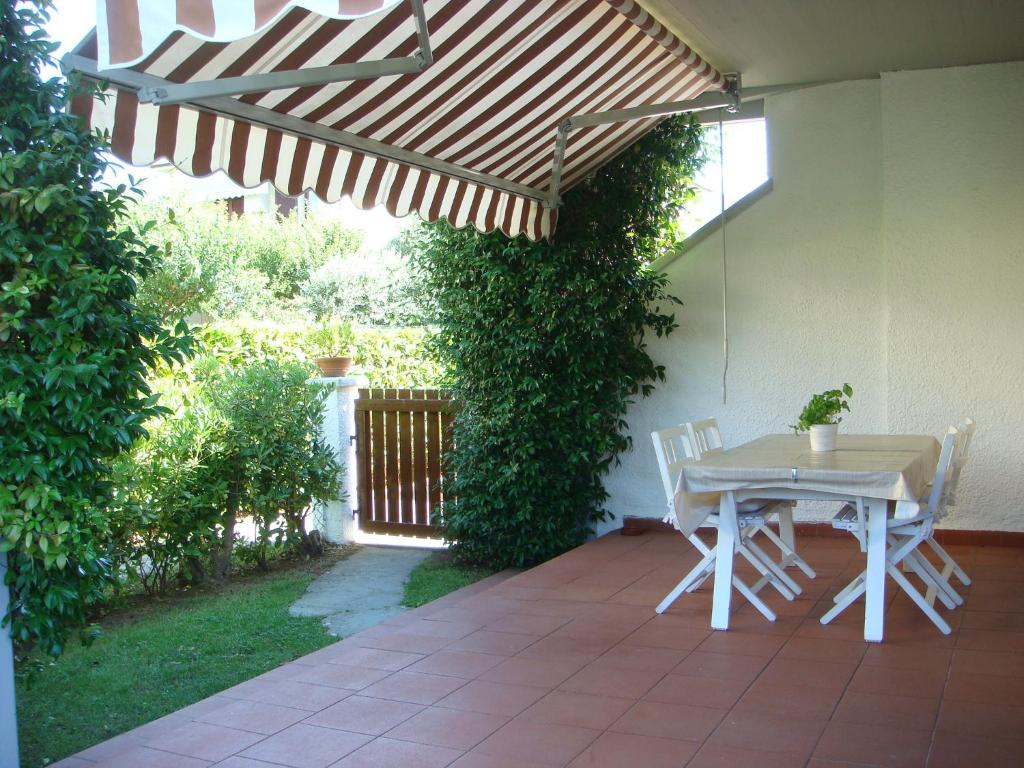 eine Terrasse mit einem Tisch und Stühlen unter einer Pergola in der Unterkunft Villetta Cinquale Versilia in Cinquale