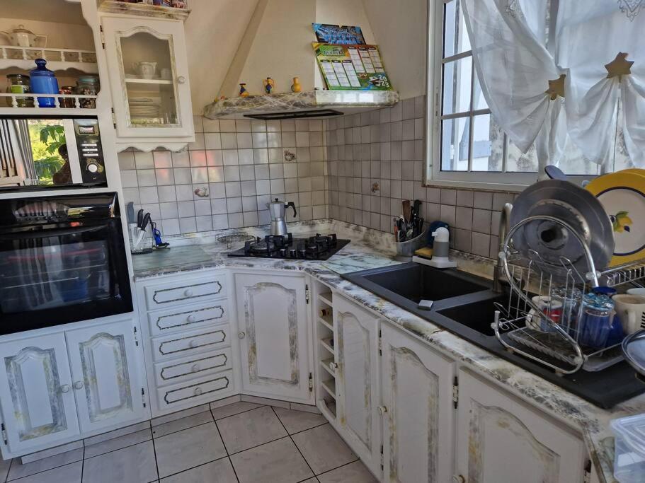 a kitchen with white cabinets and a sink at La maison du Pêcheur in Terre-de-Haut