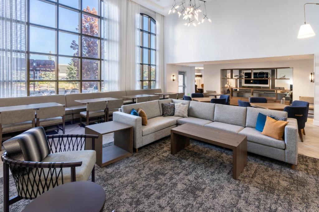 a living room with couches and tables and windows at Staybridge Suites Denver - Cherry Creek, an IHG Hotel in Denver