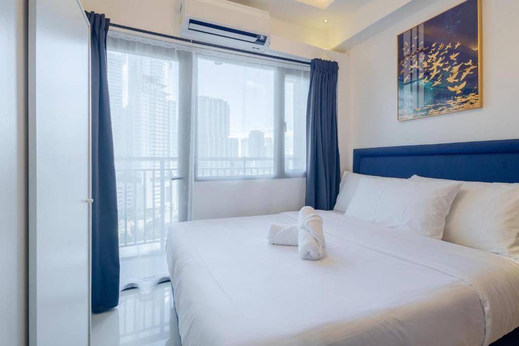 a bedroom with a large bed with a large window at Lush Residences Makati in Manila