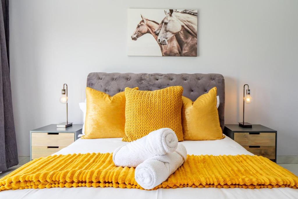 a bedroom with a bed with yellow pillows and a horse picture at Gemmell Place by HostAgents in Durban