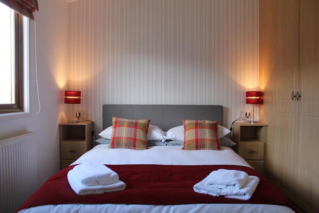 Luxury 3 bedroom lodge with free in lodge wifi في كارنفورث: غرفة نوم عليها سرير وفوط