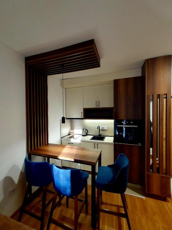 a kitchen with a wooden table and blue chairs at Apartman Felicita 2 in Zlatibor
