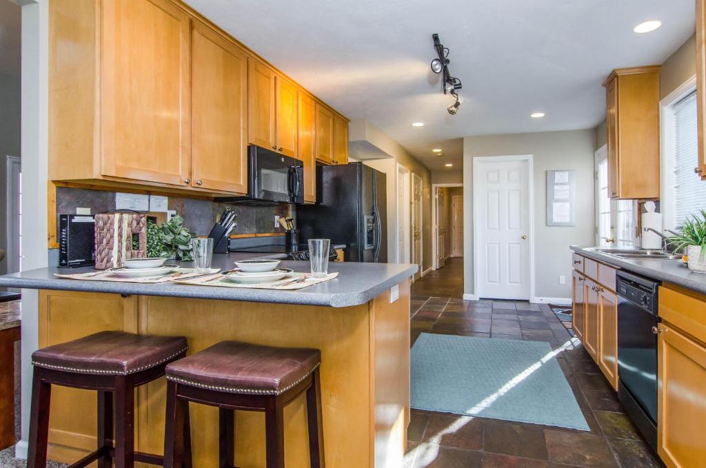 a kitchen with wooden cabinets and a island with bar stools at Union Duplex Cove and Woods in Salt Lake with Hot Tub in Midvale