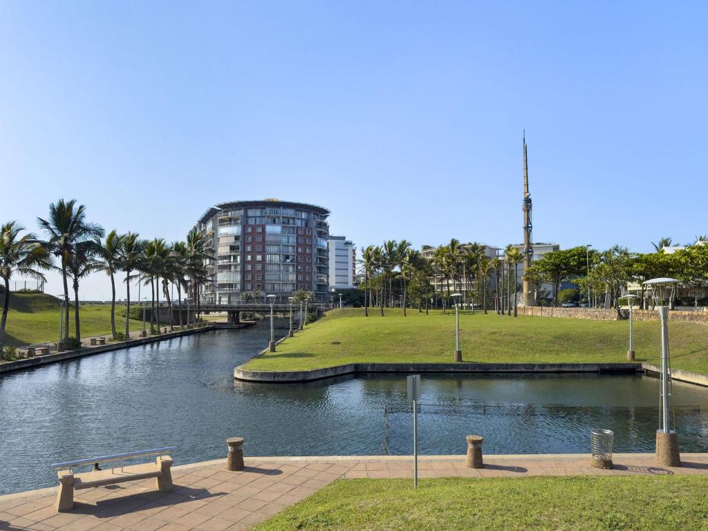 a river in a park with a building in the background at Beach Haven Townhouse in Durban
