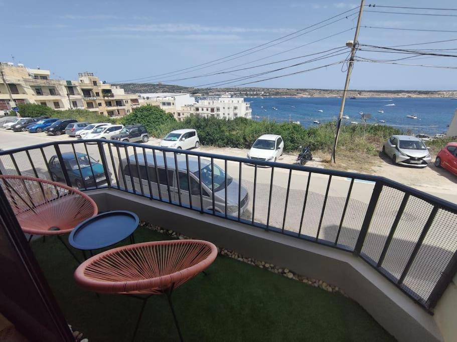 a balcony with two chairs and a view of a parking lot at Seaside Serenity - A lovely apartment with views in Mellieħa