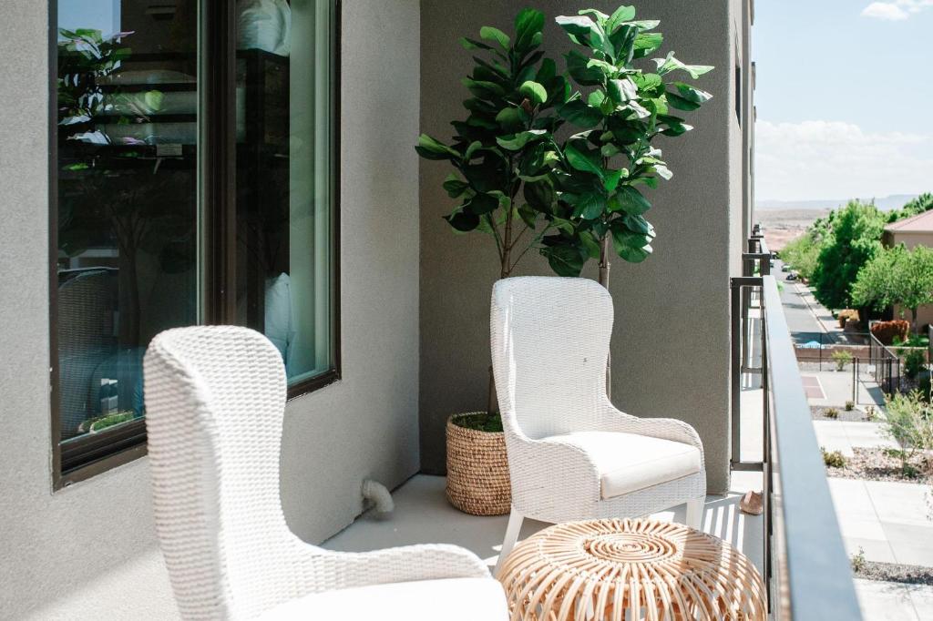 two white chairs and a potted plant on a porch at 20| Vue at Green Valley with Community Pool in St. George