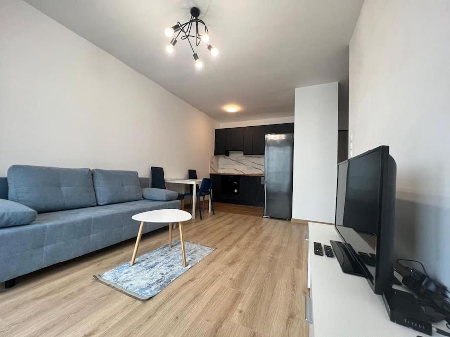 a living room with a blue couch and a table at Apartament Porto Seaside in Gdańsk