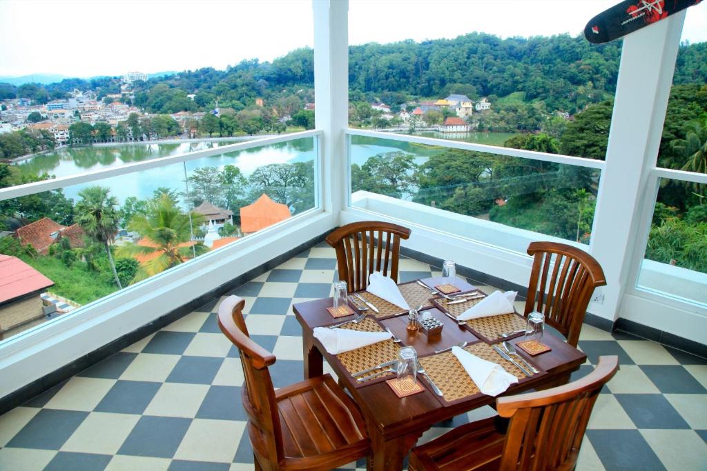a dining room with a table and chairs and large windows at Kandy Supreme Hotel in Kandy
