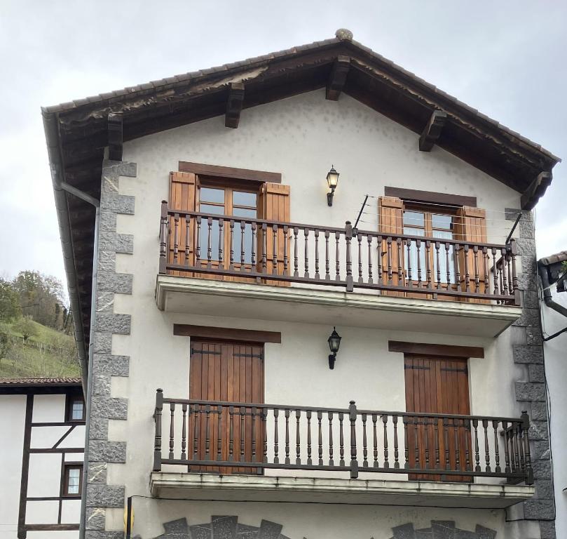 Un edificio blanco con ventanas de madera y un balcón. en Urumea Apartamento, en Goizueta