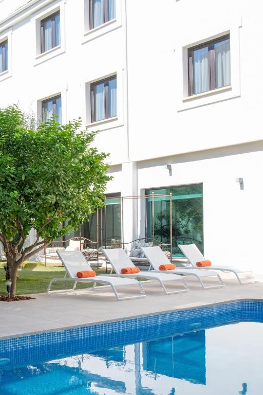 a row of lounge chairs next to a swimming pool at Hotel Infanta Leonor in Écija