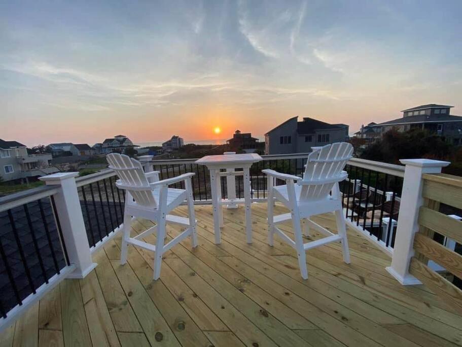 two white chairs sitting on a deck with the sunset at The Grey Goose in Duck