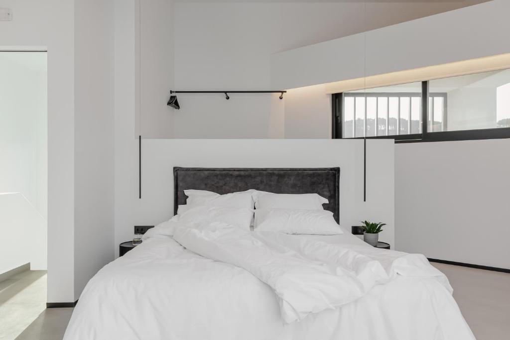Cama blanca con sábanas y almohadas blancas en No Stars - Luxury Hotel Apartments en Ioánina