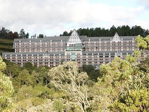 a large building in the middle of a forest at Alto do Capivari in Campos do Jordão