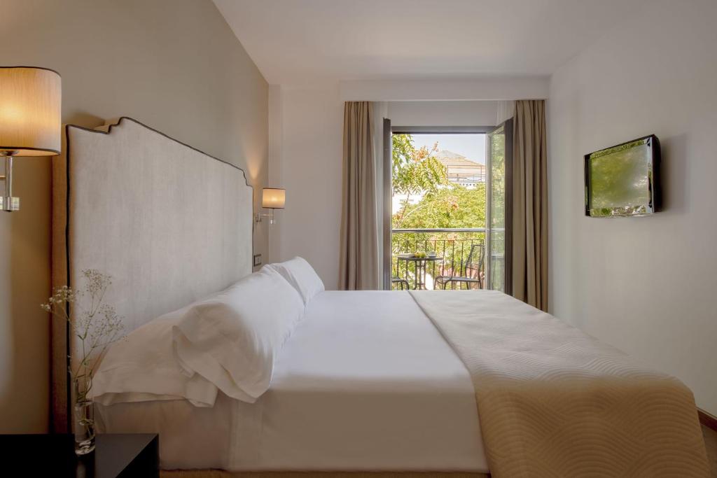 um quarto com uma grande cama branca e uma janela em Hotel Infanta Leonor em Écija