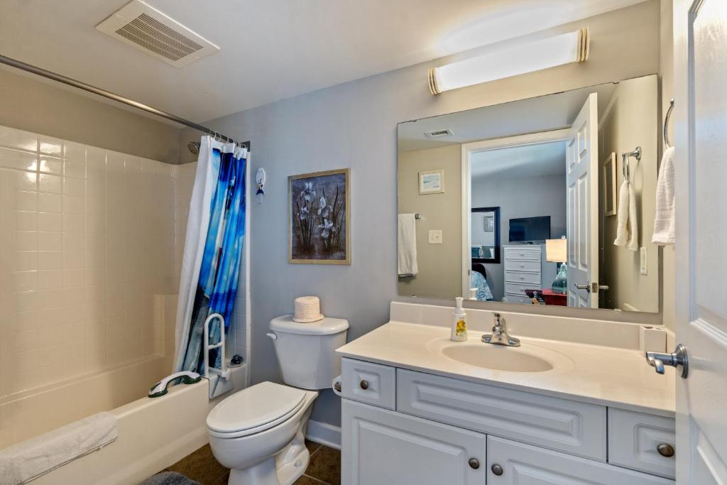 a bathroom with a toilet and a sink and a mirror at Oceanfront Get Away in Myrtle Beach