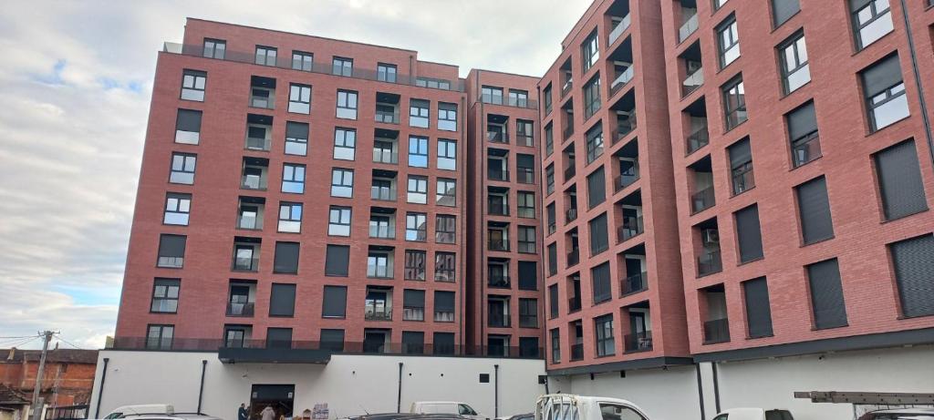 a large brick building with cars parked in front of it at The Cozy Flat in Gjakove