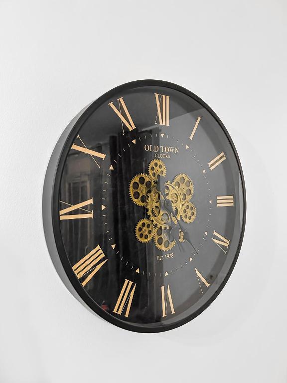 a black clock with gold roman numerals on a wall at Joyau de Pantin in Pantin