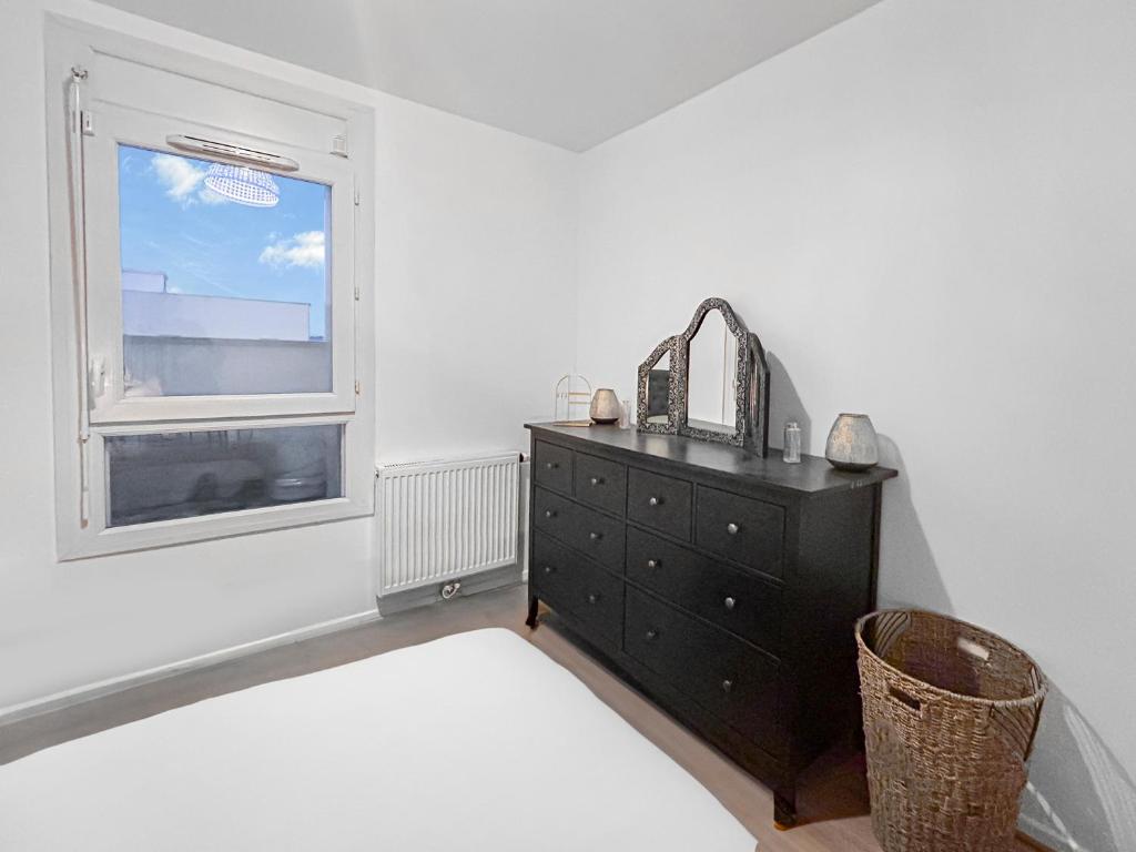 a bedroom with a black dresser and a window at Joyau de Pantin in Pantin