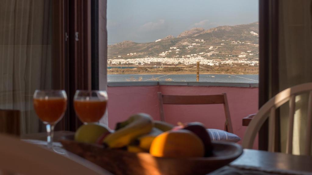 a table with a bowl of fruit and two glasses of wine at Blue Heart Luxury Suites II in Naxos Chora