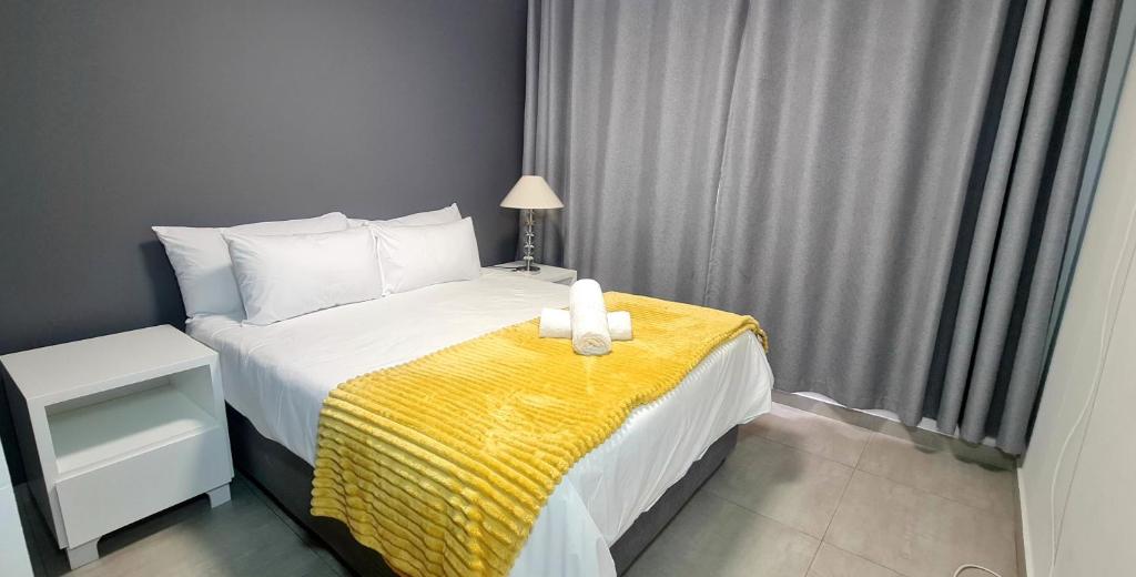 a bedroom with a bed with a yellow blanket at Penzance - Beach Accommodation in Durban