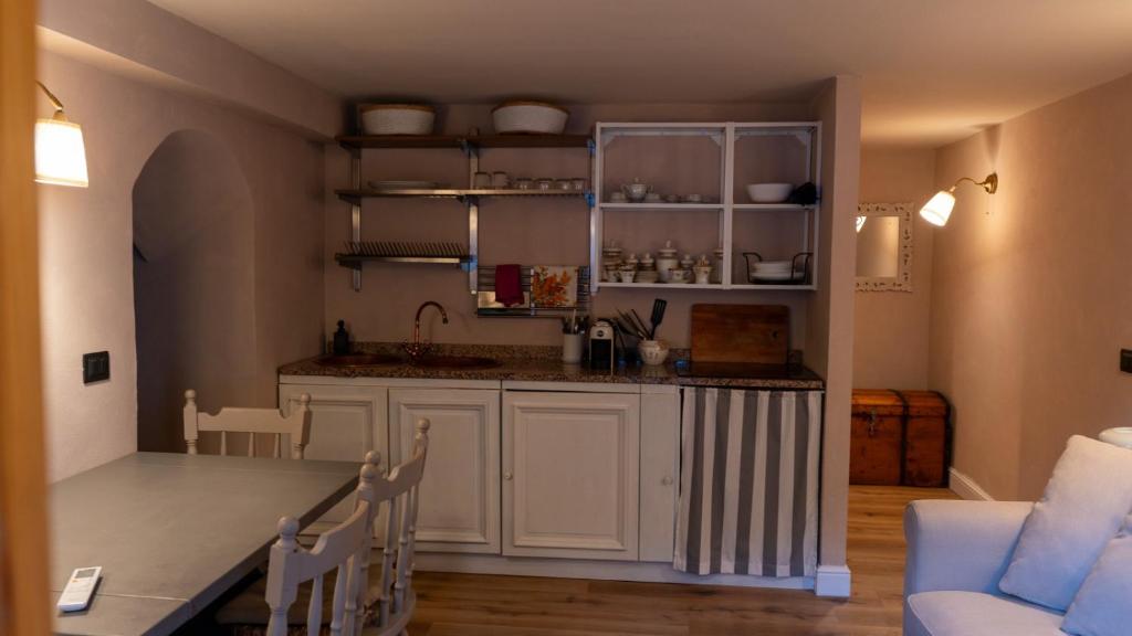 a kitchen with white cabinets and a table in a room at Bilocale a due passi dal mare immerso nel verde in Castiglioncello