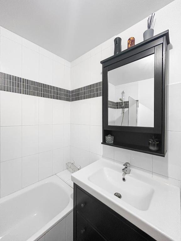 a white bathroom with a sink and a mirror at Joyau de Pantin in Pantin