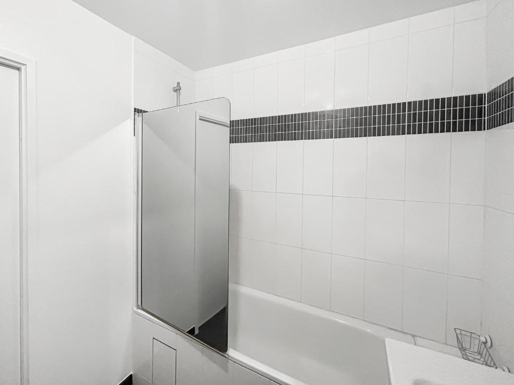 a white bathroom with a shower and a mirror at Joyau de Pantin in Pantin