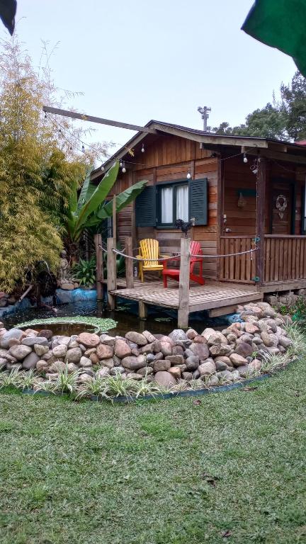 a log cabin with a deck and a pond in the yard at Chalé Cafofo in Campo Alegre