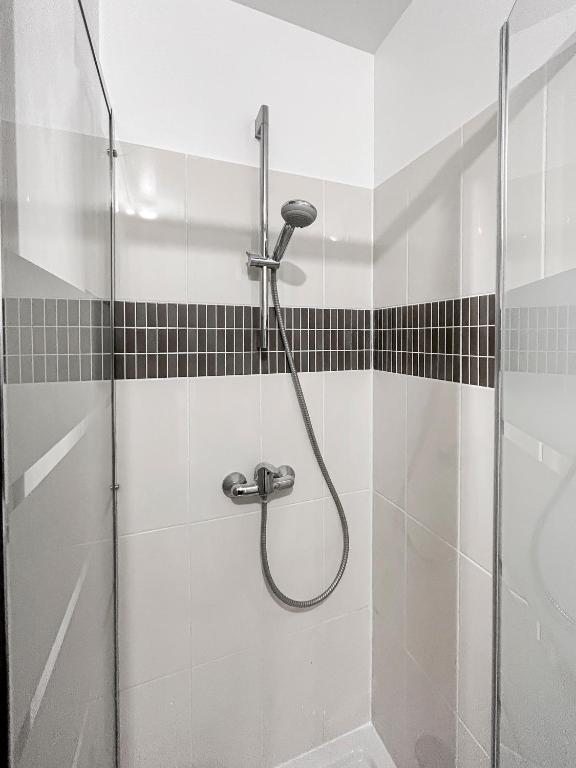a shower in a bathroom with black and white tiles at Joyau de Pantin in Pantin