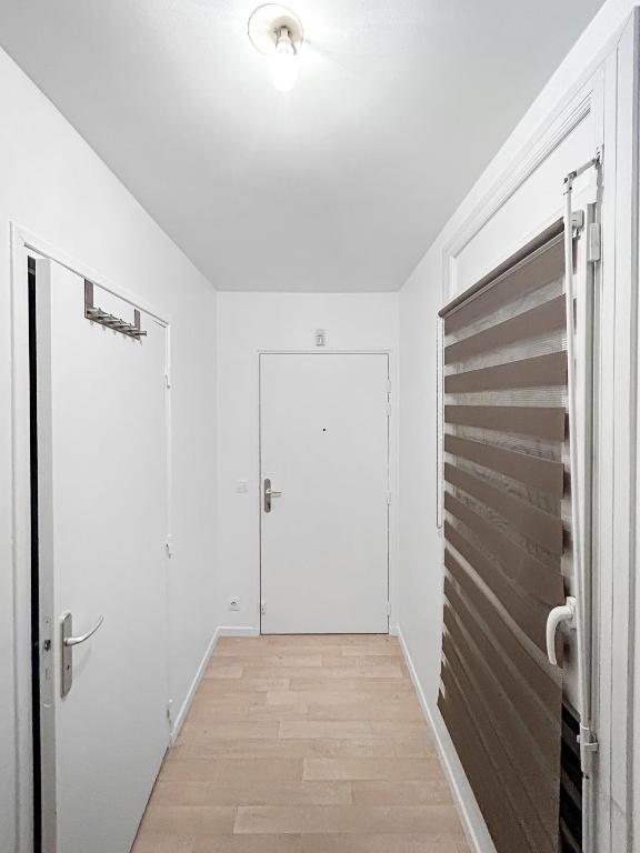a hallway with white walls and a door and wooden floors at Joyau de Pantin in Pantin