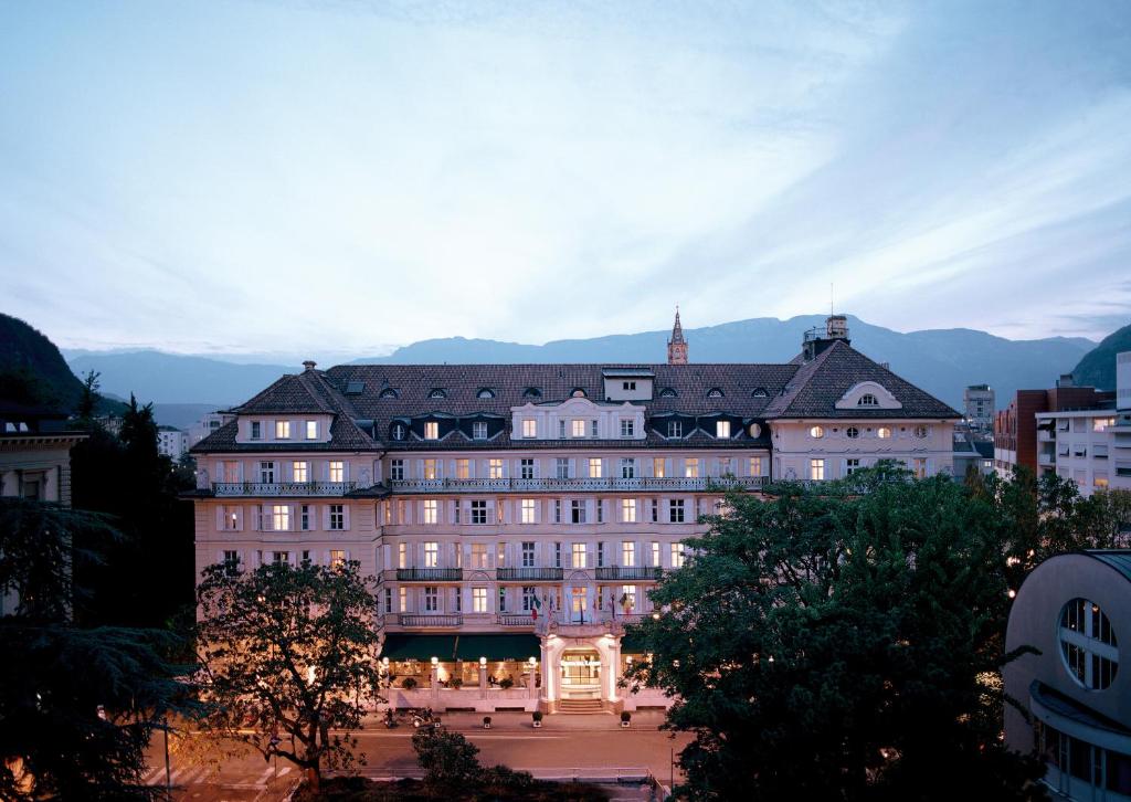 un gran edificio se ilumina al anochecer en Parkhotel Laurin, en Bolzano