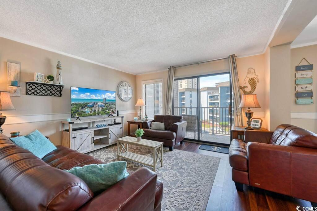 a living room with leather furniture and a balcony at Family friendly, cozy, home at the beach in Myrtle Beach