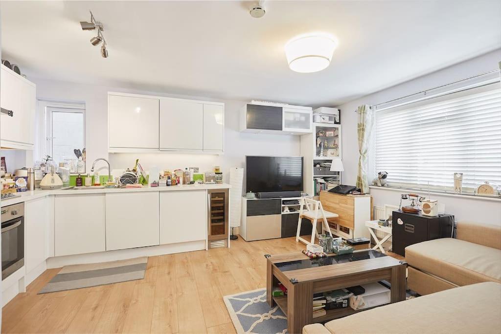 uma cozinha com armários brancos e uma sala de estar em A lovely and comfortable flat in South London em Thornton Heath