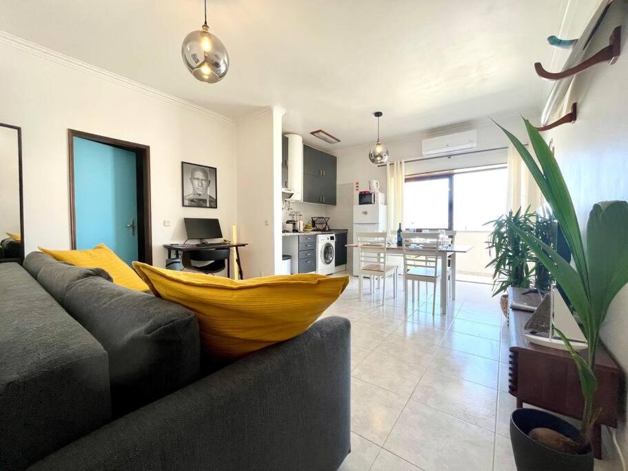 a living room with a couch with a yellow pillow on it at CASA COSY - Caparica Beach and Surf Apartment in Costa da Caparica