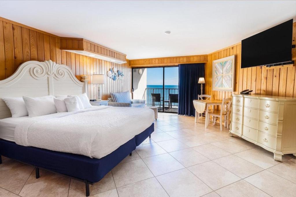 een slaapkamer met een groot bed en een woonkamer bij Gentle Whispers Oceanfront King Room 6th Fl in Pawleys Island