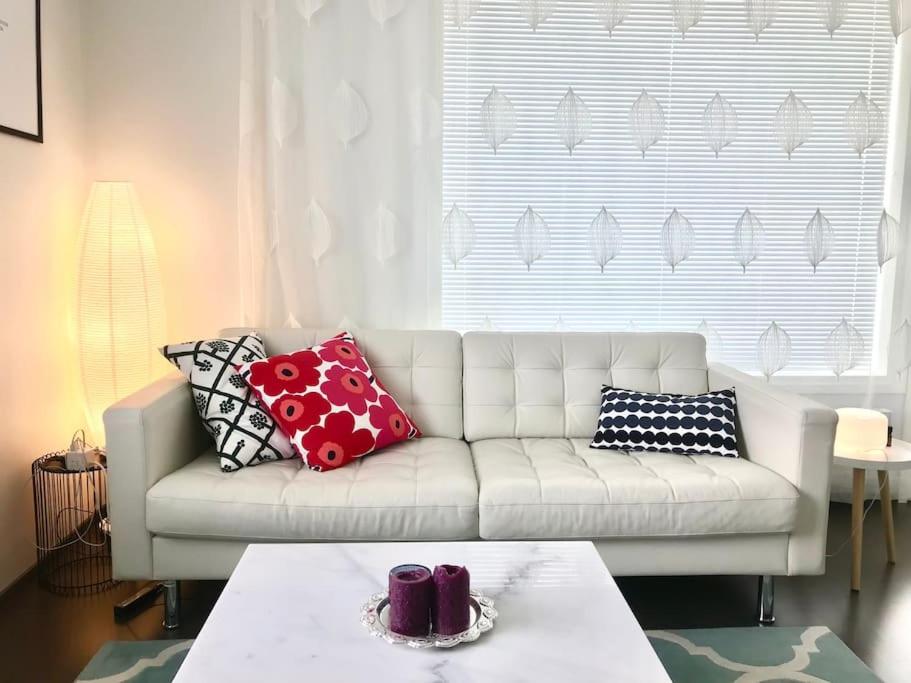 a living room with a white couch with pillows on it at Brand New and Cozy Modern Studio! WithAirCondition in Turku