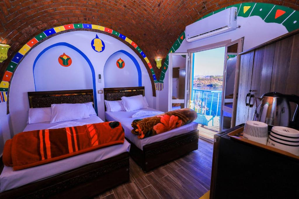 - une chambre avec 2 lits dans une chambre avec une fenêtre dans l'établissement Nubian Popeye - Roof top - Nile View, à Assouan