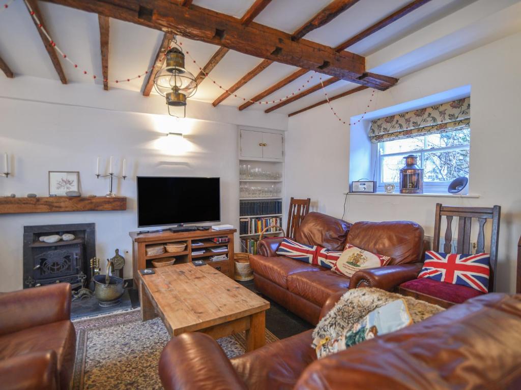 een woonkamer met lederen meubels en een flatscreen-tv bij Naunton Cottage in Lyme Regis