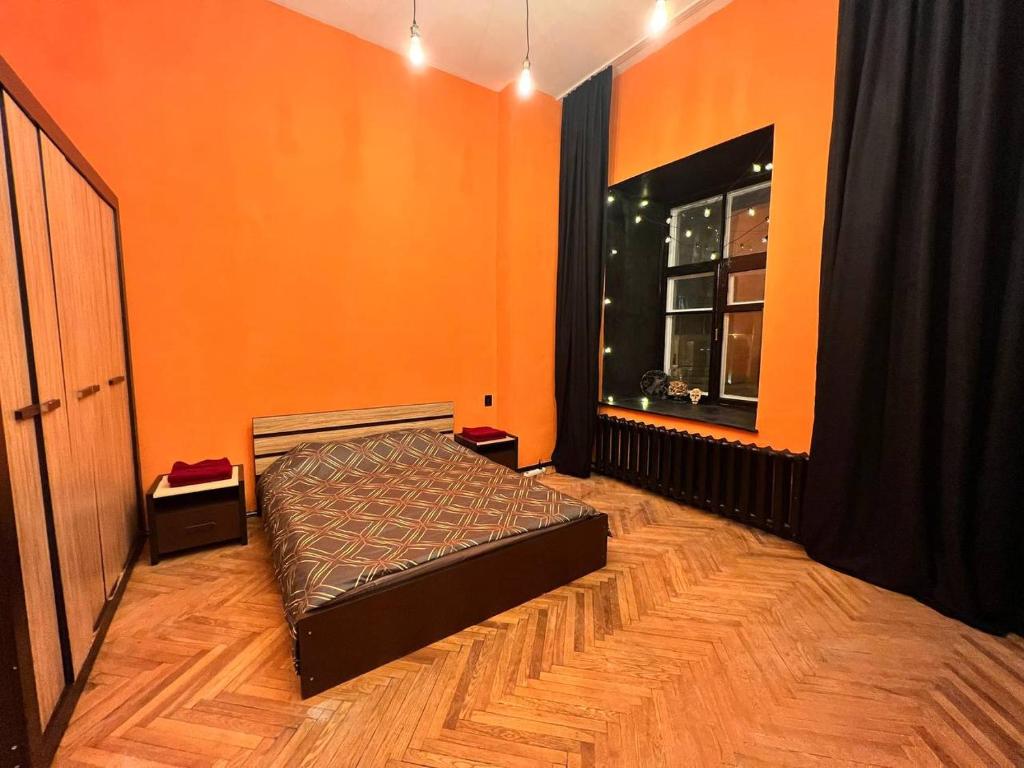 orangefarbenes Zimmer mit einem Bett und einem Fenster in der Unterkunft KyivHome Loft on Maidan Independence Square in Kiew