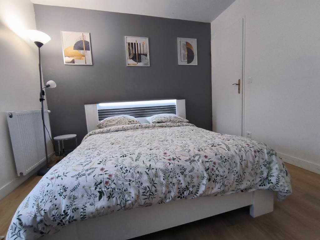 a bedroom with a bed with a floral bedspread at Appartement Jelyad Angelus proche Disney in Chanteloup-en-Brie