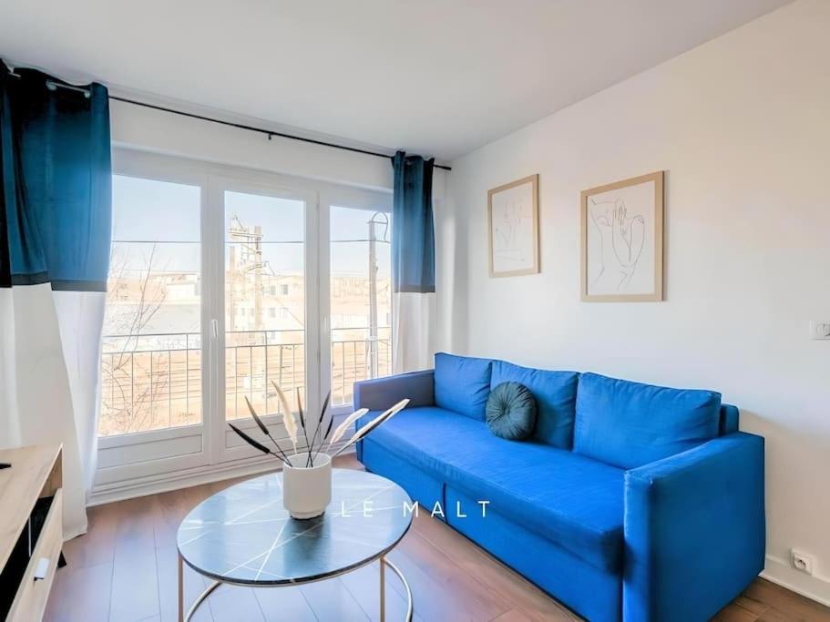 een blauwe bank in een woonkamer met een glazen tafel bij Le Malt - Centre ville - Orly - Proche Gare - Elégant à la française in Juvisy-sur-Orge