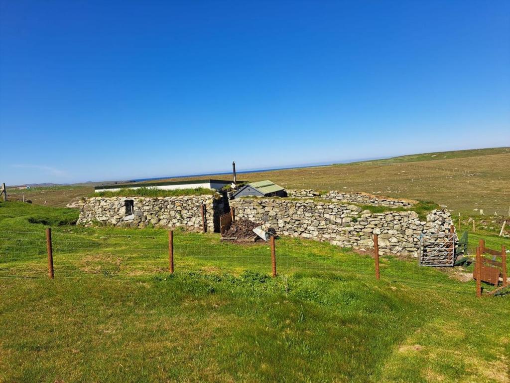an old stone building in the middle of a field at Squealing Pig Bothy in Bragor