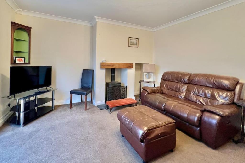 a living room with a leather couch and a flat screen tv at Fantastic central home in Dean