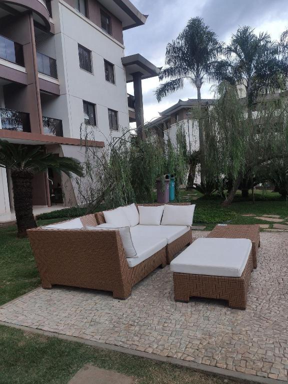 a couch and tables on a patio in front of a building at L207 Apartamento em resort à beira lago in Brasilia