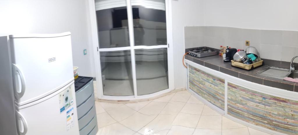 a kitchen with a sink and a refrigerator at boughaz appartement Terrasse in Hajreien