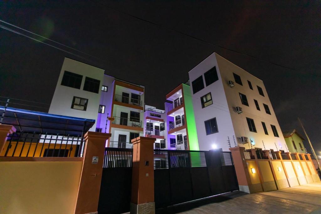a group of buildings at night with a fence at Washington Apartments - just 25mins drive from the Airport in Kwashieman