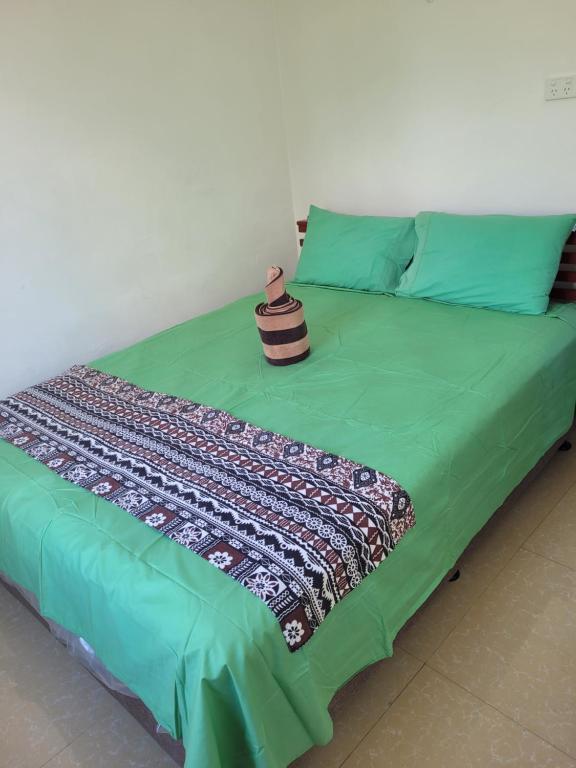 a bed with a green comforter and a pillow at Holiday Home in Lautoka