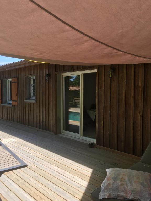 a house with a wooden deck with a sliding glass door at comme chez vous in Taussat-les-Bains